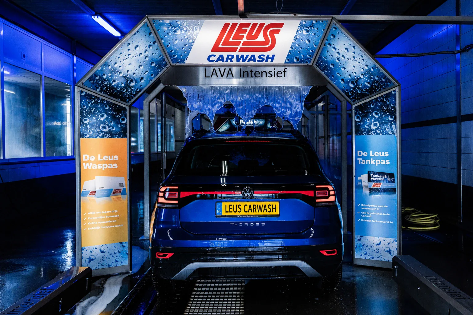 Blauwe auto rijdt een blauw verlichte wasstraat in, onder een boog met een gordijn van schuim