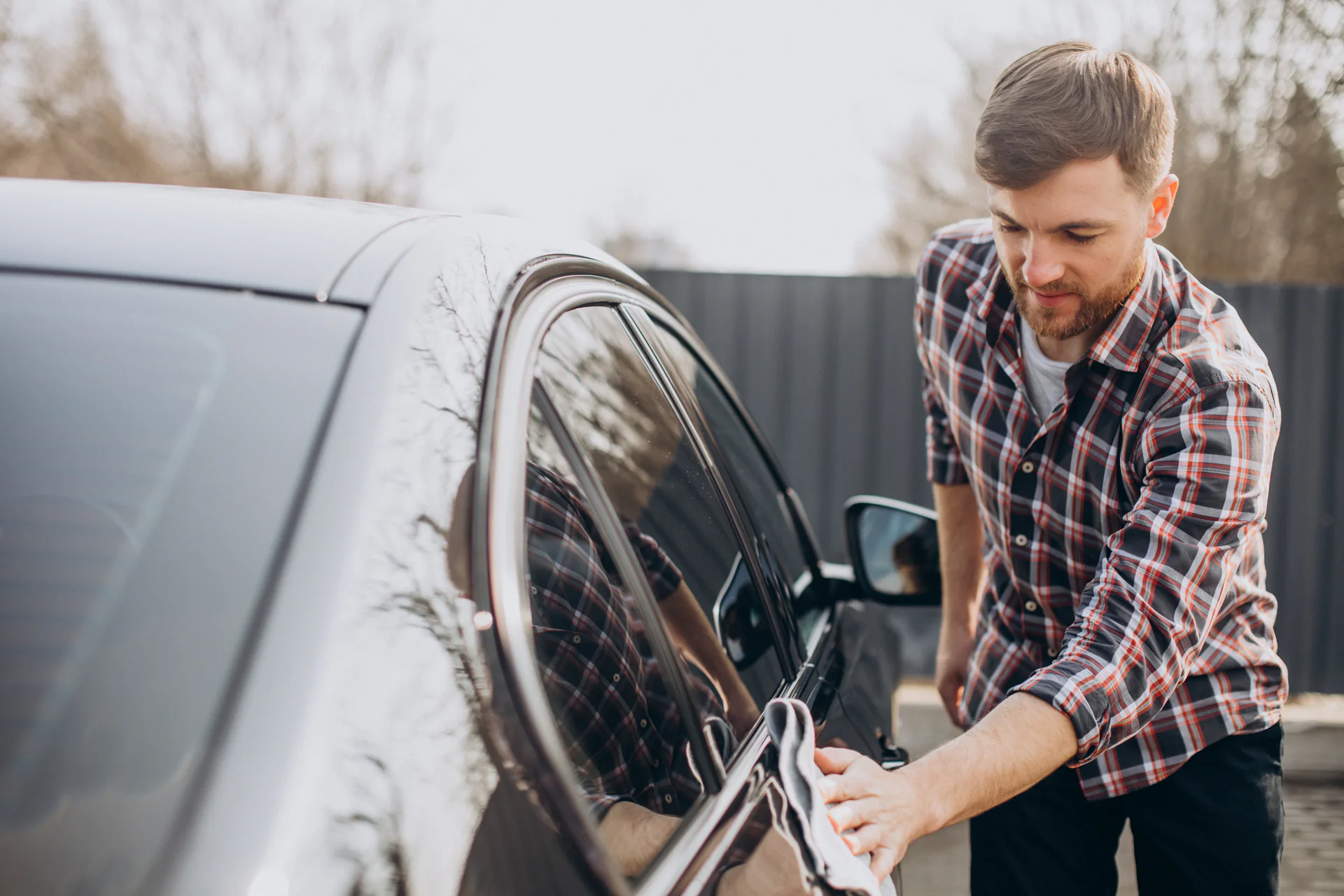 Man droogt een net gewassen auto af bij de carwash
