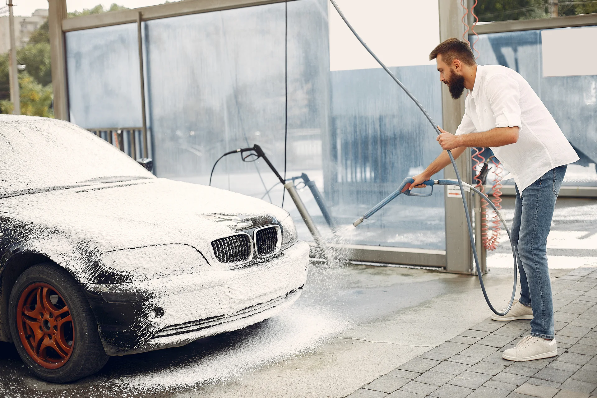 Man spuit de onderkant van een auto onder het schuim af