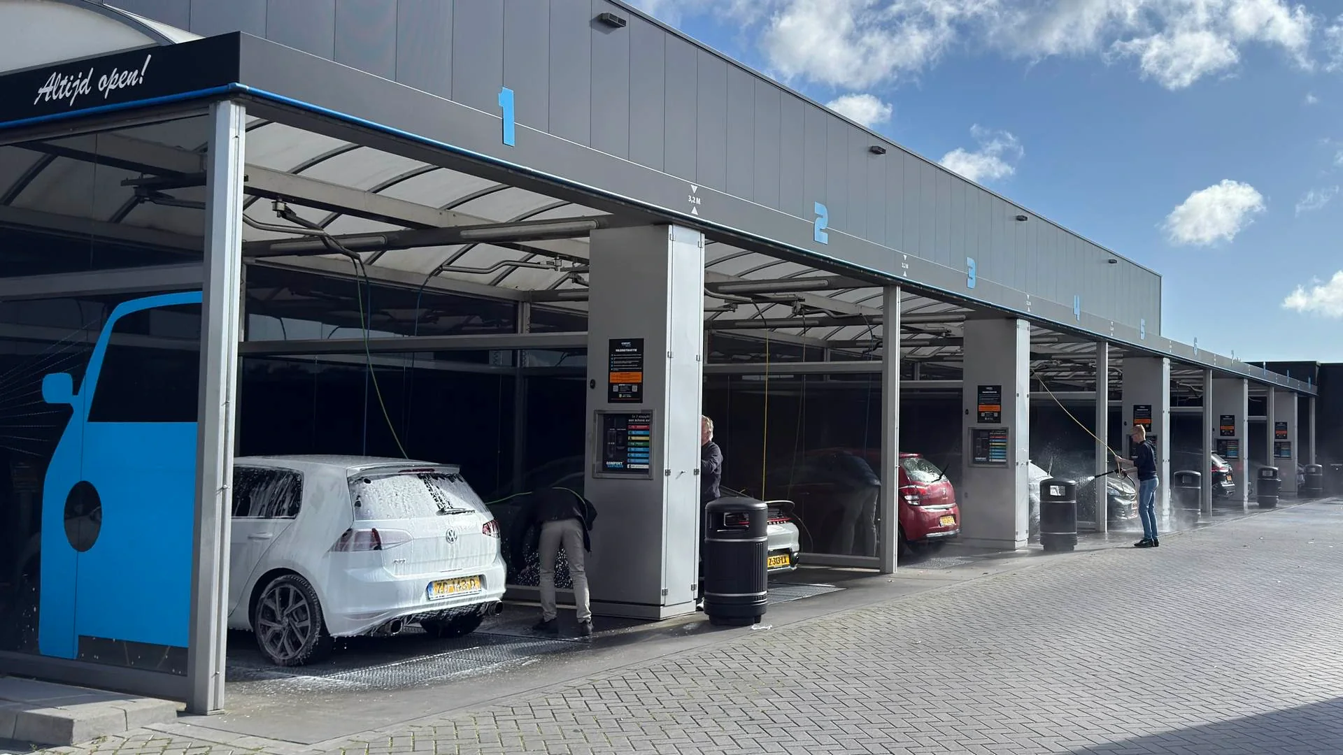 Overdekte wasboxen met geparkeerde auto's ernaast