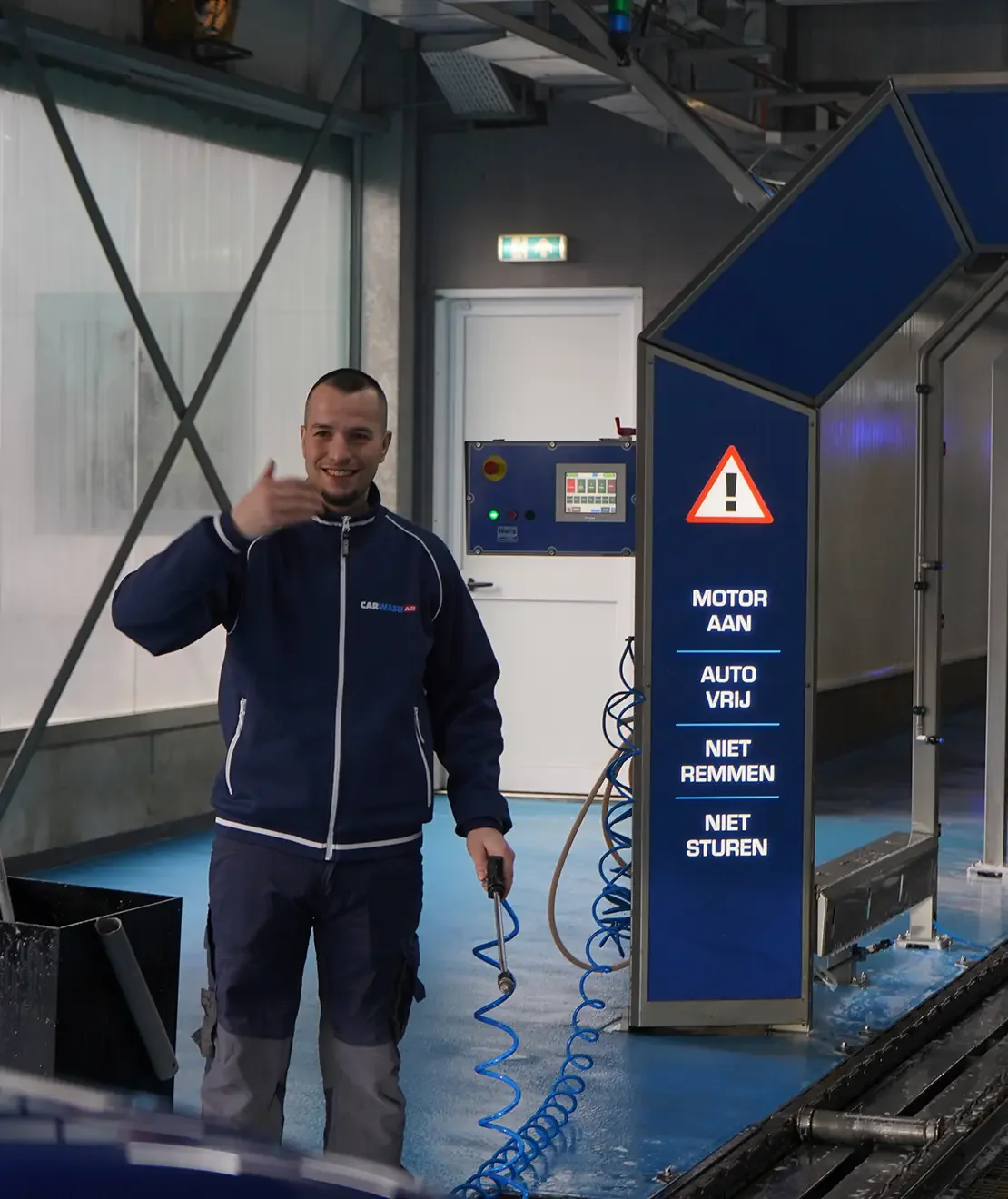 Medewerker begeleidt een auto de wastunnel in – Carwash A2 Zaltbommel, Zaltbommel