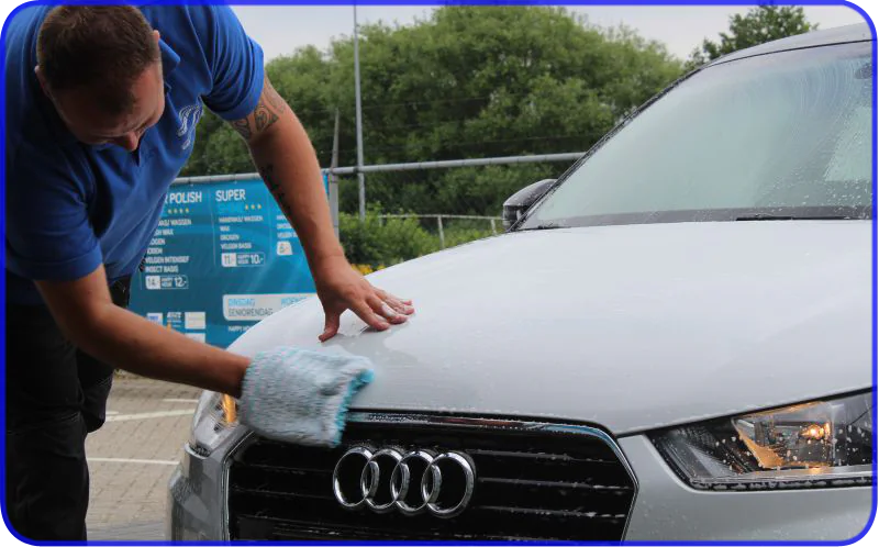 Medewerker wast een auto bij het blauwe programmabord – Stuart Carcare Elst, Elst
