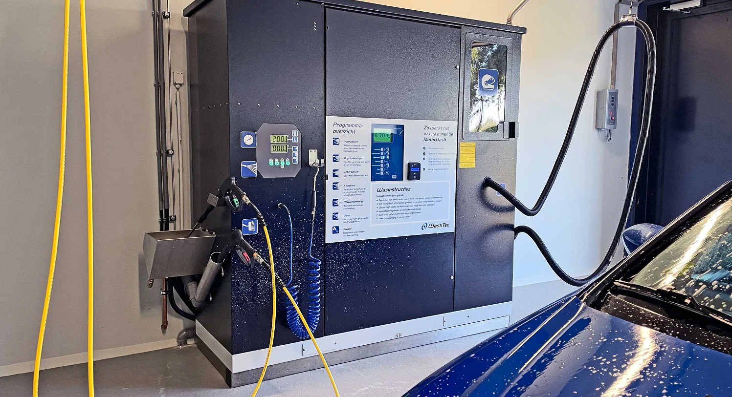 Wasprogramma’s, slangen en handdroger naast een blauwe auto – ALLSAFE Wasbox Weesp, Weesp