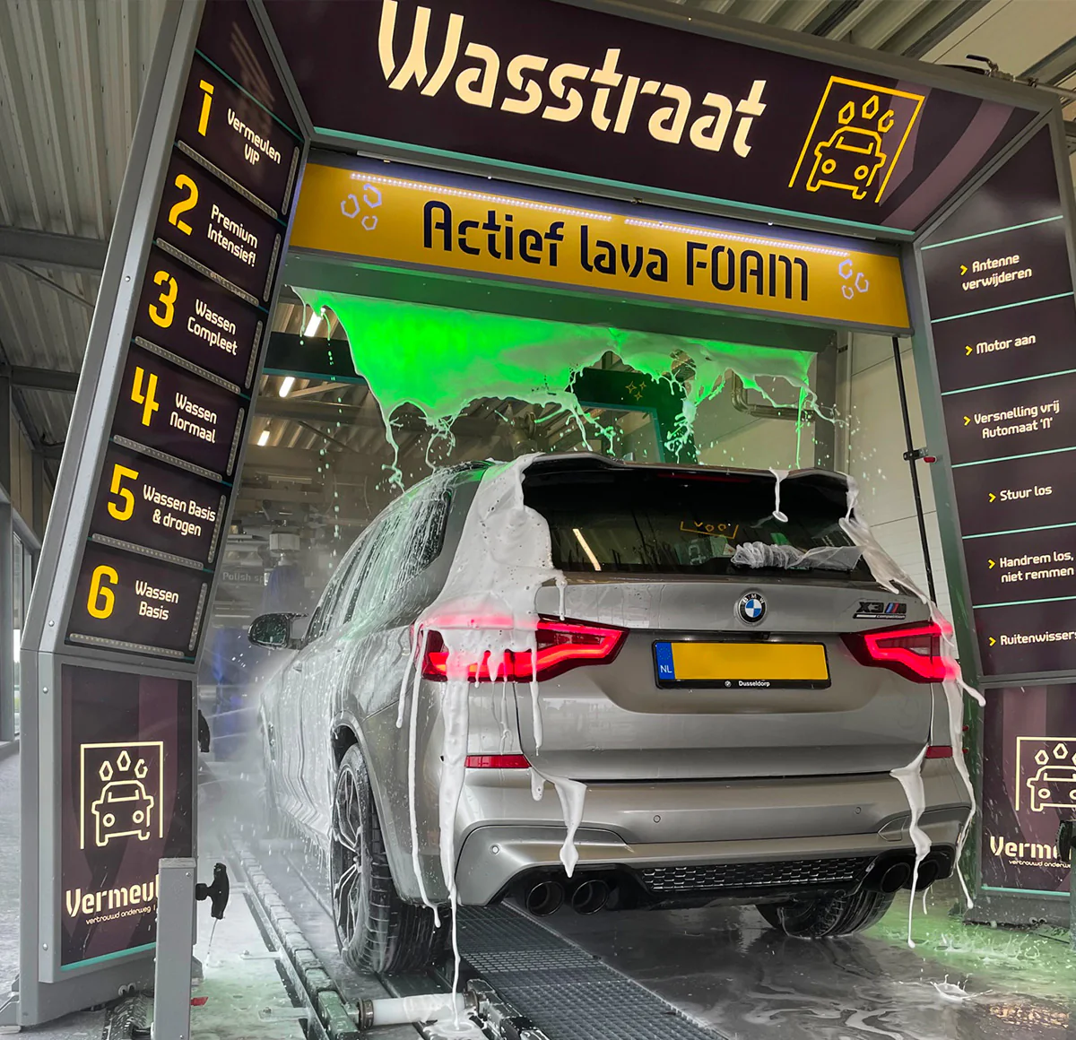 Auto onder gekleurd lava-schuim in een wasstraat
