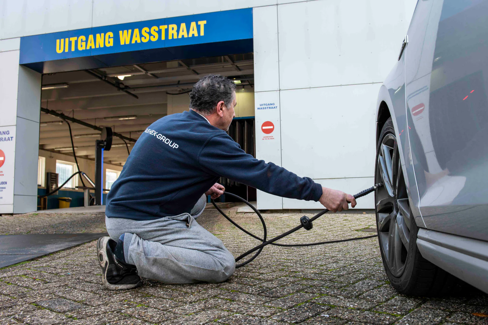 Man geknield bij een velg met de hogedrukspuit