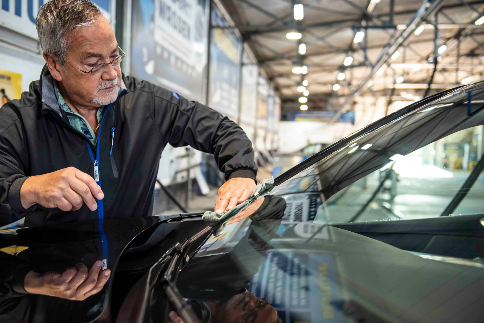Man veegt de voorruit van een auto af met een doek in een overdekte carwash