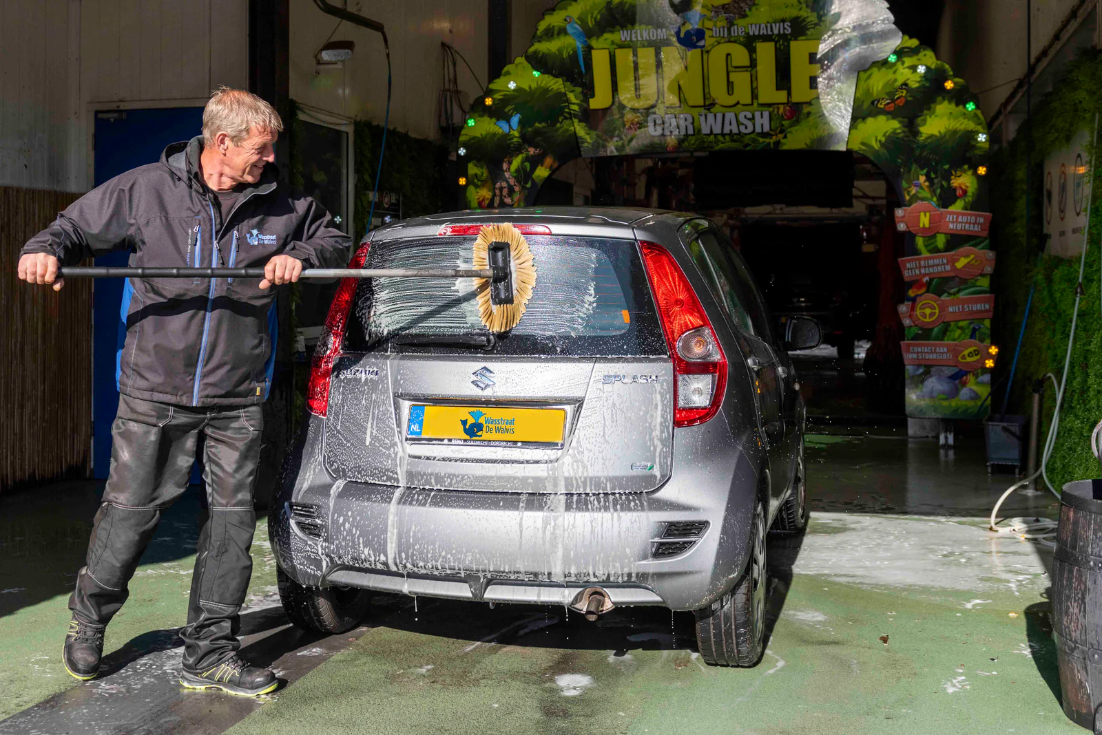 Man wast een auto met een borstel